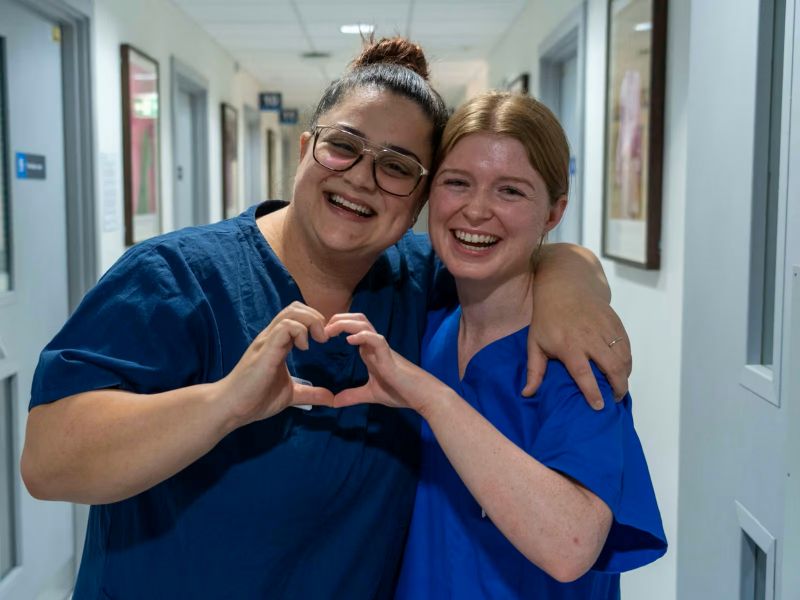 Two nurses holding their hands together in the shape of a heart
